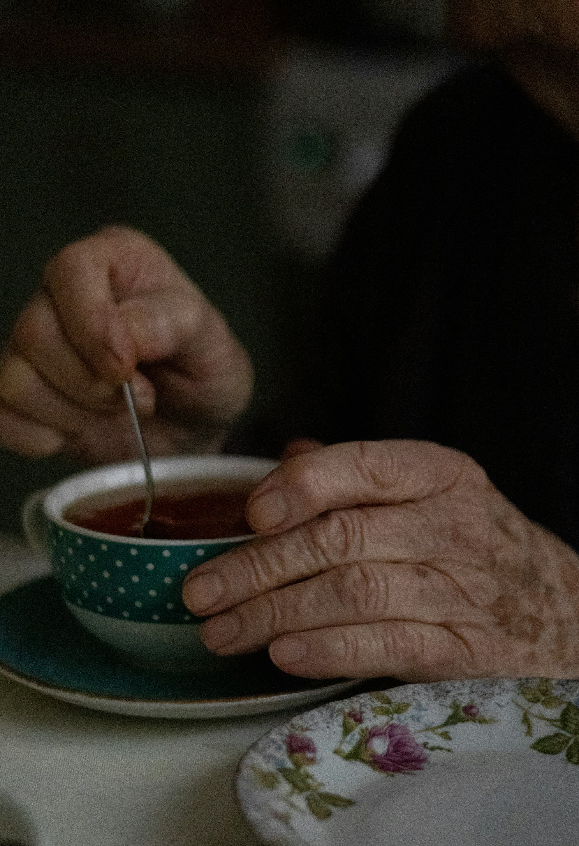 An older person stirring a cup of tea