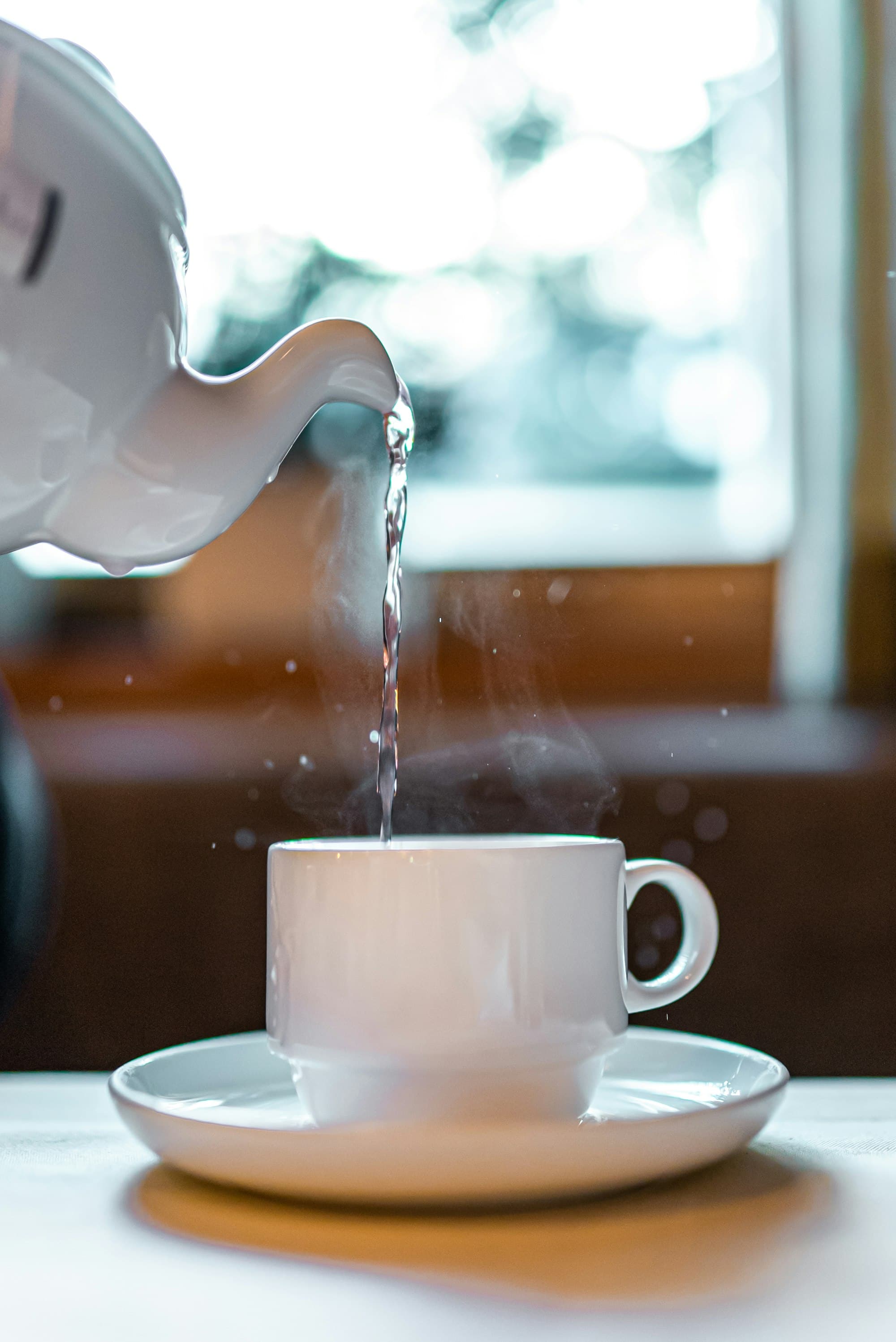 Hot water being poured from a kettle into a mug